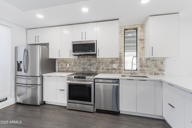 kitchen with sink, appliances with stainless steel finishes, white cabinetry, dark hardwood / wood-style floors, and tasteful backsplash