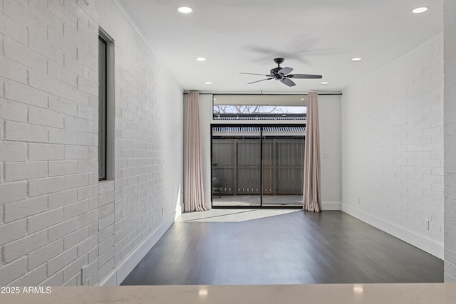 unfurnished room with brick wall, dark hardwood / wood-style floors, and ceiling fan