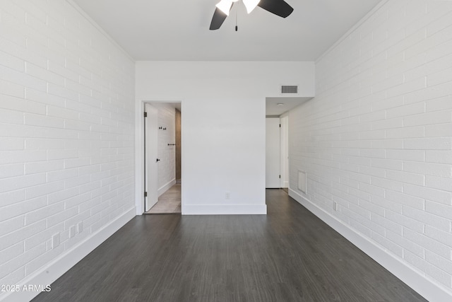 spare room with ceiling fan, brick wall, and dark hardwood / wood-style floors