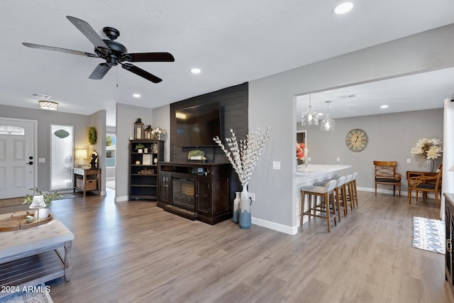 living room featuring ceiling fan with notable chandelier and light wood-type flooring