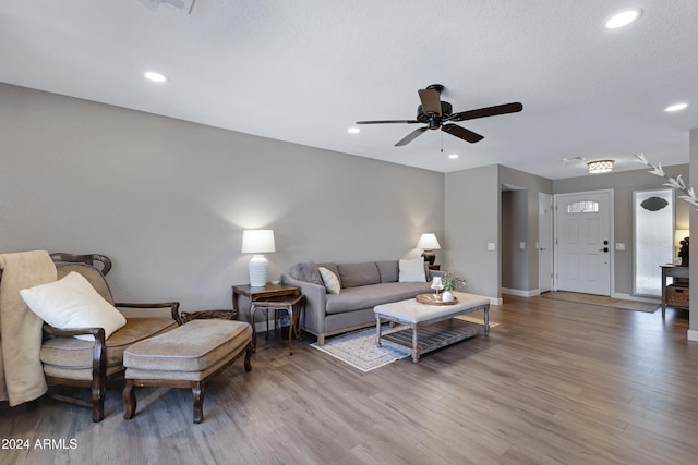 living room with a textured ceiling, wood-type flooring, and ceiling fan