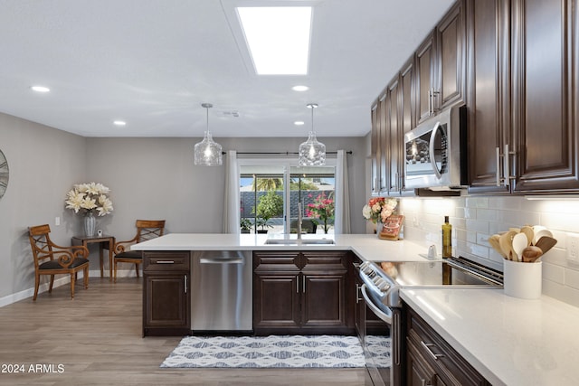 kitchen featuring hanging light fixtures, appliances with stainless steel finishes, light wood-type flooring, dark brown cabinetry, and sink