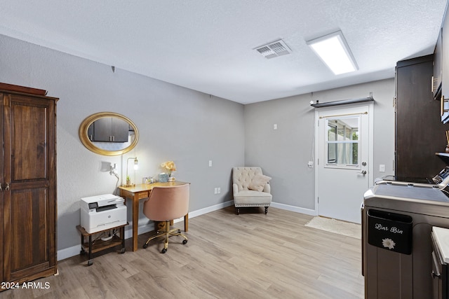 office area featuring light hardwood / wood-style flooring, a textured ceiling, and washer and clothes dryer