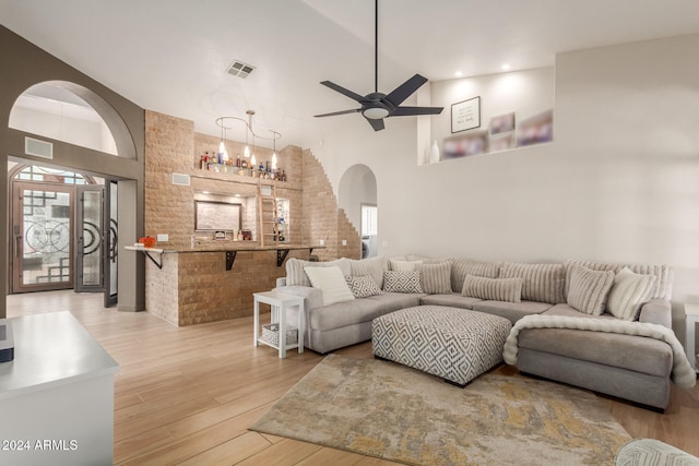 living room featuring high vaulted ceiling, hardwood / wood-style flooring, and ceiling fan with notable chandelier