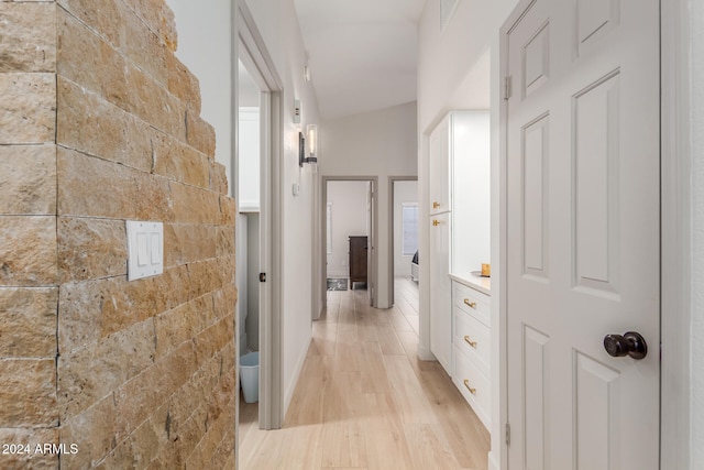 hallway with lofted ceiling and light hardwood / wood-style flooring