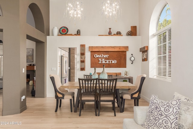 dining area featuring a high ceiling, a chandelier, and light hardwood / wood-style flooring