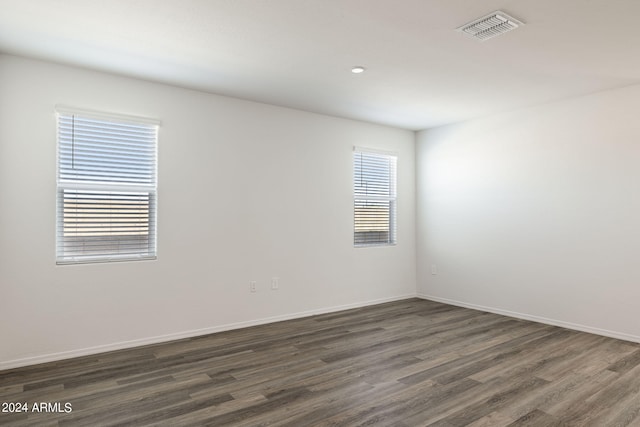 empty room featuring visible vents, baseboards, and dark wood finished floors