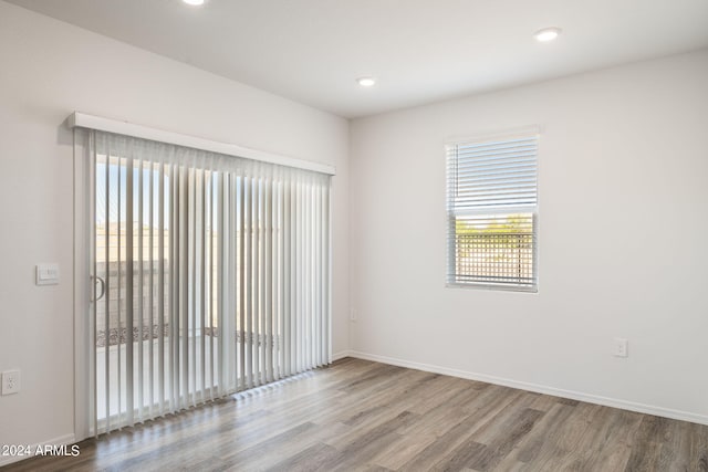 unfurnished room with recessed lighting, wood finished floors, and baseboards