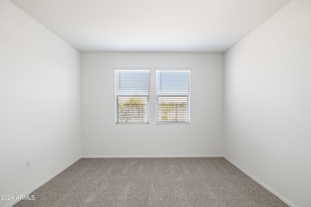 carpeted spare room featuring baseboards