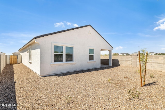 back of house with a tiled roof, a fenced backyard, and stucco siding