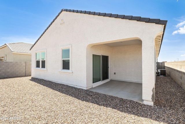 rear view of property with stucco siding, a patio, central AC, and a fenced backyard