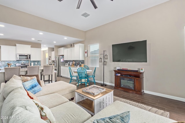 living room featuring ceiling fan and dark hardwood / wood-style floors