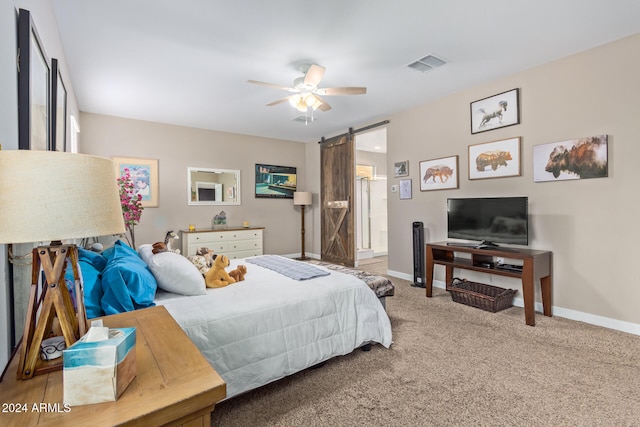 carpeted bedroom featuring a barn door and ceiling fan