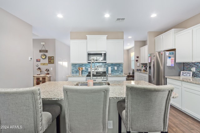 kitchen featuring white cabinetry, appliances with stainless steel finishes, an island with sink, and dark hardwood / wood-style flooring