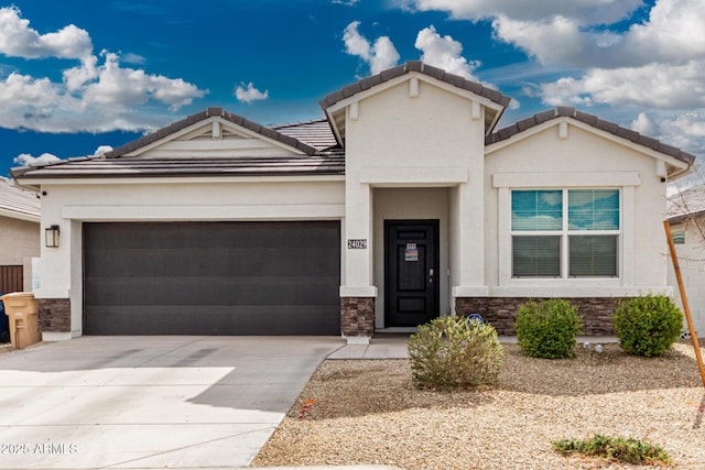 view of front of house with an attached garage, driveway, stone siding, a tiled roof, and stucco siding