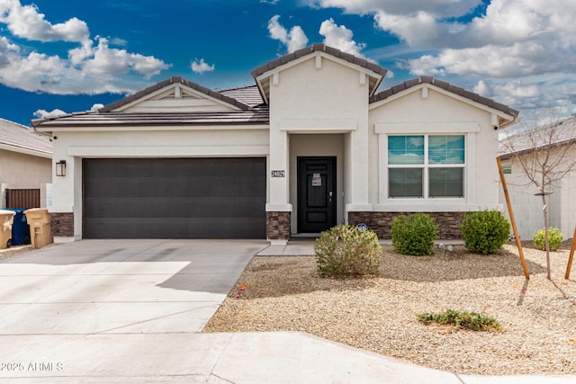 view of front of house featuring a garage, driveway, stone siding, a tile roof, and stucco siding