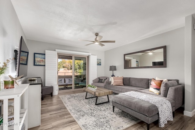 living room with a textured ceiling, ceiling fan, and light hardwood / wood-style flooring