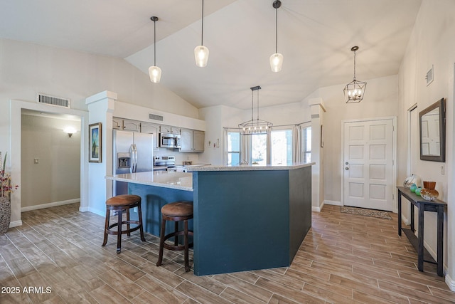 kitchen with appliances with stainless steel finishes, a chandelier, high vaulted ceiling, and hanging light fixtures