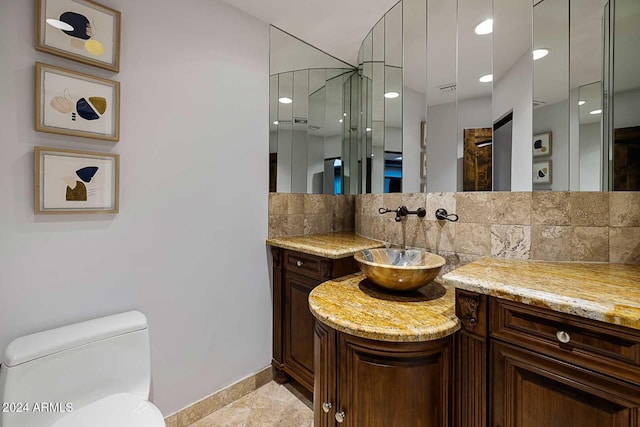 bathroom with vanity, a shower, toilet, and tasteful backsplash