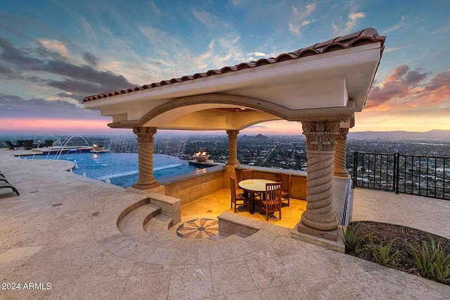 pool at dusk featuring a gazebo, an outdoor bar, pool water feature, and a patio area