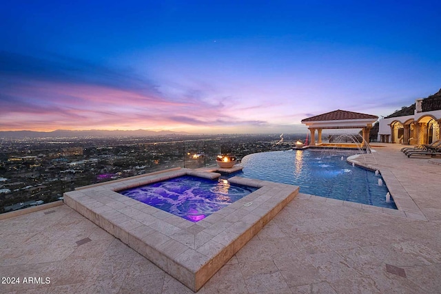 pool at dusk featuring pool water feature, a patio, an in ground hot tub, and a gazebo