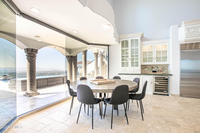 dining area with a water view, wine cooler, and ornate columns