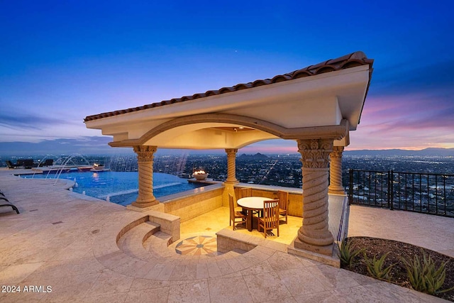 patio terrace at dusk featuring a mountain view, a gazebo, and pool water feature