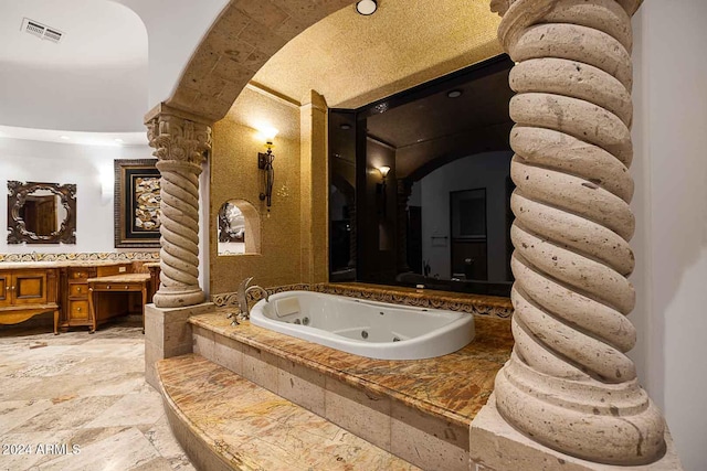 bathroom featuring vanity, a washtub, and ornate columns