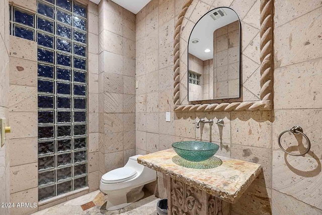 bathroom with sink, tile walls, and toilet