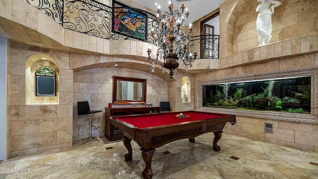 recreation room with tile walls, a high ceiling, billiards, and a notable chandelier