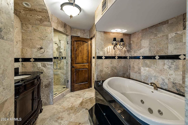 bathroom with independent shower and bath, vanity, and tile walls