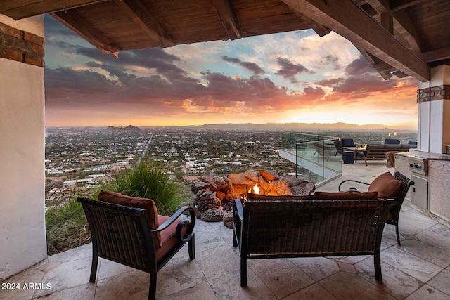 balcony at dusk featuring a patio, a mountain view, and an outdoor hangout area