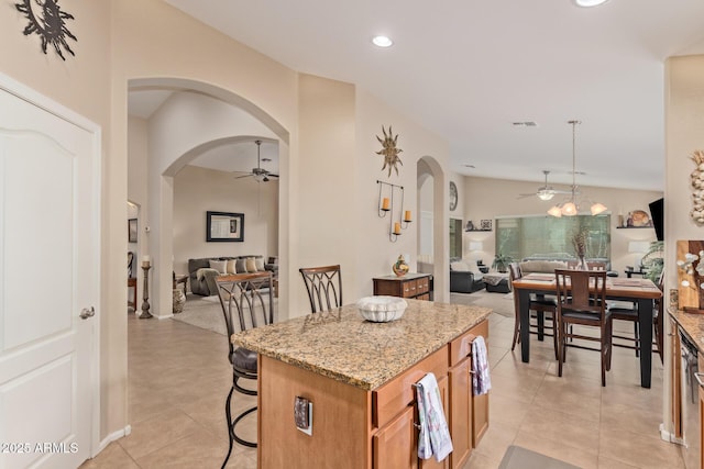 kitchen with pendant lighting, ceiling fan, a breakfast bar area, and a kitchen island