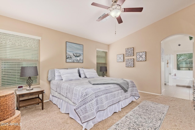 carpeted bedroom with lofted ceiling, ceiling fan, and ensuite bath