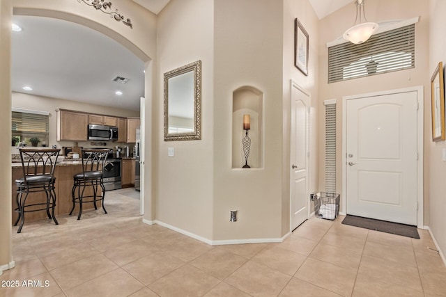 foyer entrance with a towering ceiling and light tile patterned floors