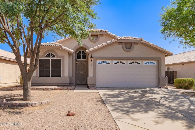 mediterranean / spanish house with a tiled roof, driveway, a garage, and stucco siding