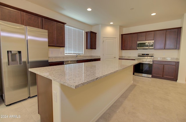 kitchen featuring a center island, light stone countertops, appliances with stainless steel finishes, sink, and light tile patterned flooring