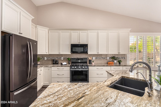 kitchen with white cabinetry, stainless steel appliances, sink, and vaulted ceiling