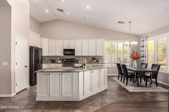 kitchen featuring a wealth of natural light, a kitchen island with sink, fridge, and white cabinets