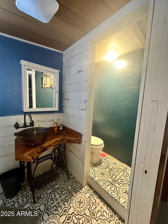 bathroom featuring wooden walls, a sink, tile patterned flooring, wood ceiling, and toilet