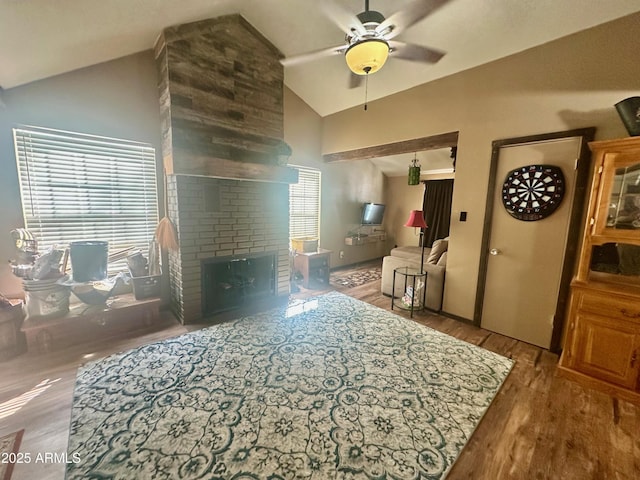 living room with a fireplace, high vaulted ceiling, wood finished floors, and ceiling fan