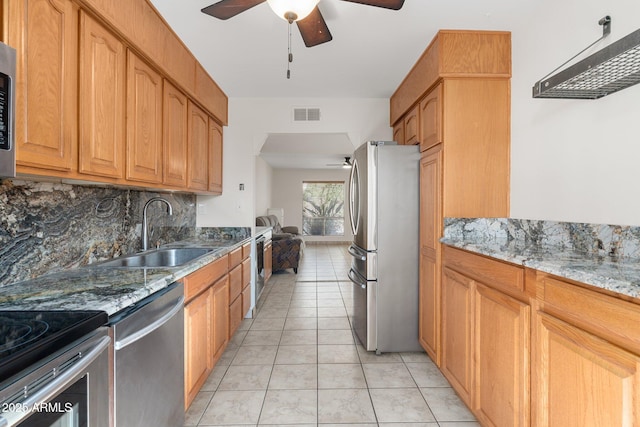 kitchen with stainless steel appliances, sink, backsplash, light tile patterned floors, and stone counters