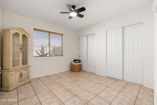 unfurnished bedroom with ceiling fan, two closets, and light tile patterned floors