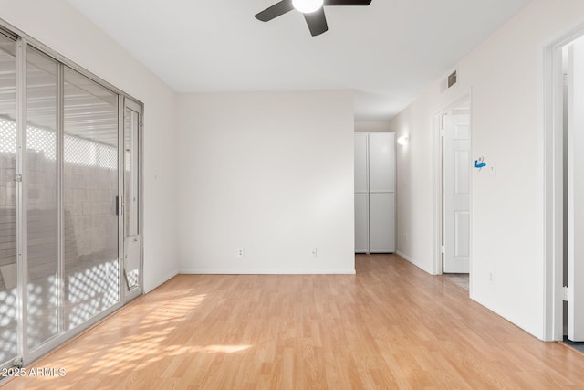 empty room featuring ceiling fan, a wealth of natural light, and light wood-type flooring