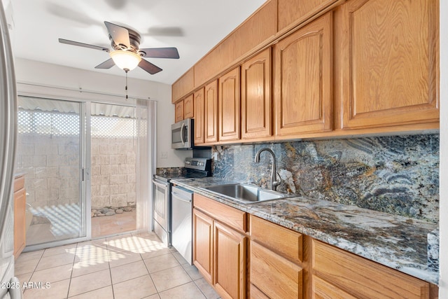 kitchen featuring appliances with stainless steel finishes, dark stone countertops, decorative backsplash, sink, and light tile patterned floors