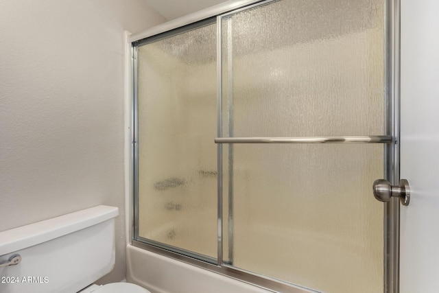 bathroom featuring enclosed tub / shower combo and toilet