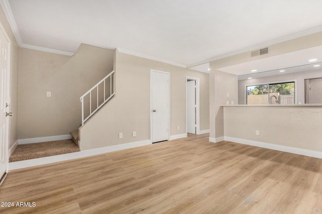 unfurnished living room with sink, light wood-type flooring, and crown molding