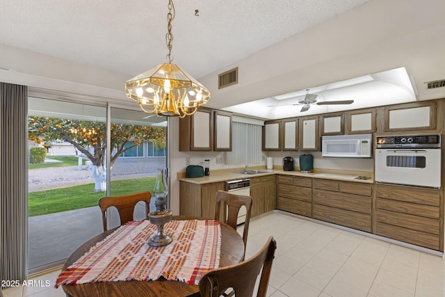 dining area with ceiling fan with notable chandelier, sink, a textured ceiling, and light tile patterned floors