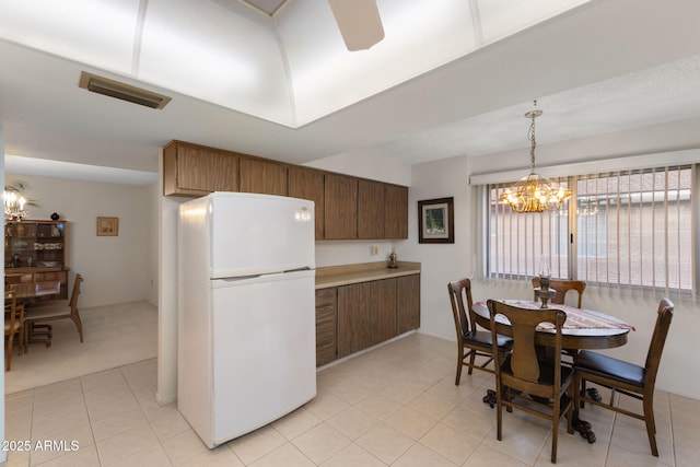 kitchen featuring white refrigerator, hanging light fixtures, light tile patterned floors, and a chandelier