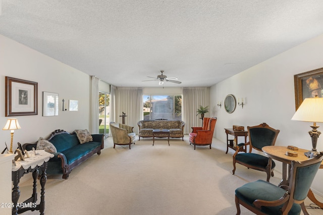 living room with ceiling fan, carpet flooring, and a textured ceiling